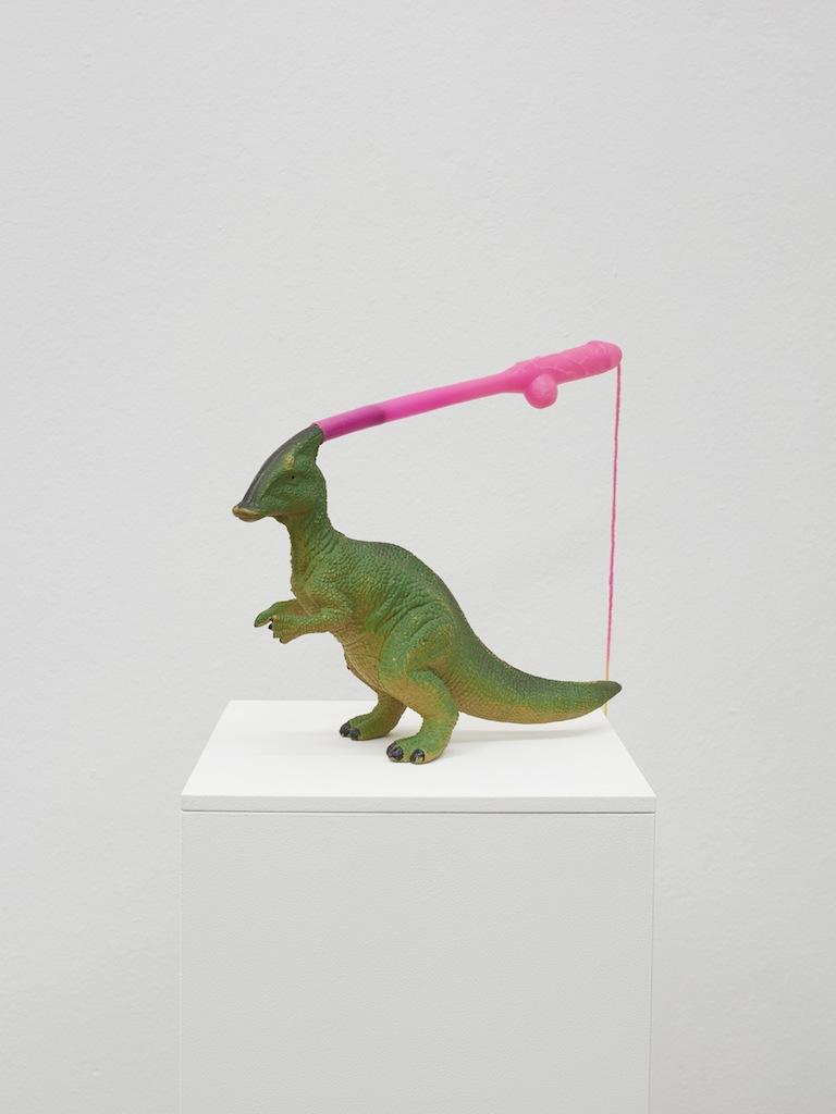 Danny McDonald, <i>The Last of his Kind at The End of The Line</i>, 2015, plastic dinosaur, novelty straw, rainbow yarn, 22 x 27 x 27 cm